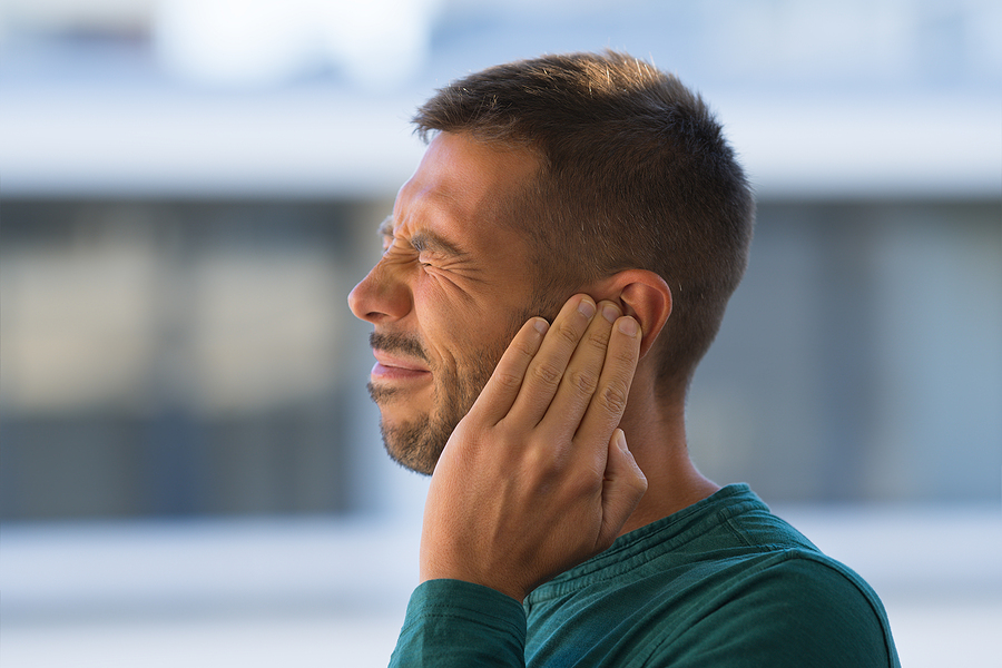 Man holding his ear in pain - Tinnitus concept