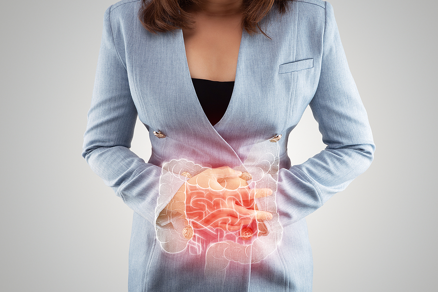 IBS concept - woman with Irritable Bowel Syndrome holding her lower abdominal. Overlay of the digestive tract over image.