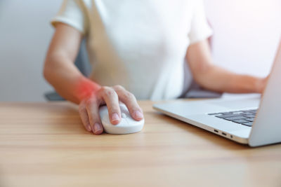 woman with carpal tunnel syndrome experiencing hand pain while working on a laptop 