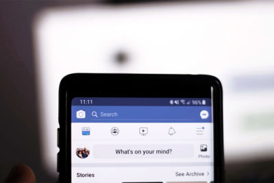 top of smartphone open to facebook - social media surveillance concept