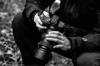 black and white image of private investigator with DSLR camera equipped with a telephoto lens -disability inquiry and surveillance concept