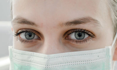 closeup of woman's eyes with surgical mask - COVID-19 concept