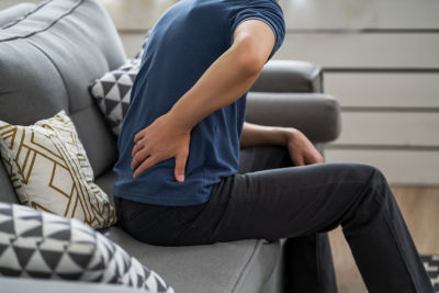 man suffering from chronic back pain on couch