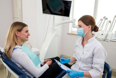 young female dentist talking with patient in dentist chair