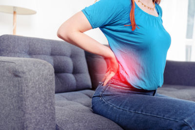 woman with back injury on couch - disability insurance after being fired concept